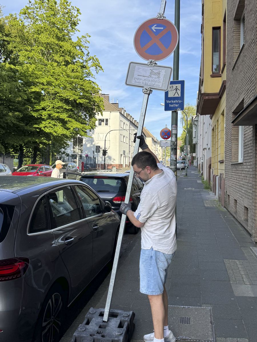 Aufrichten der Halteverbotsschilder neben parkenden Autos am Straßenrand